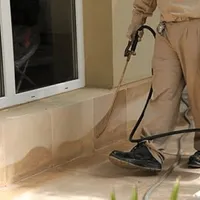 General pest control technician spraying exterior perimeter around a home in Colorado Springs, CO