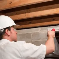 Termite inspection technician checking a basement wall and framing for termite activity in Colorado Springs, CO